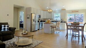 Uma sala de estar espaçosa com uma mesa de centro, um sofá e um espaço de jantar com cadeiras e mesa de madeira.