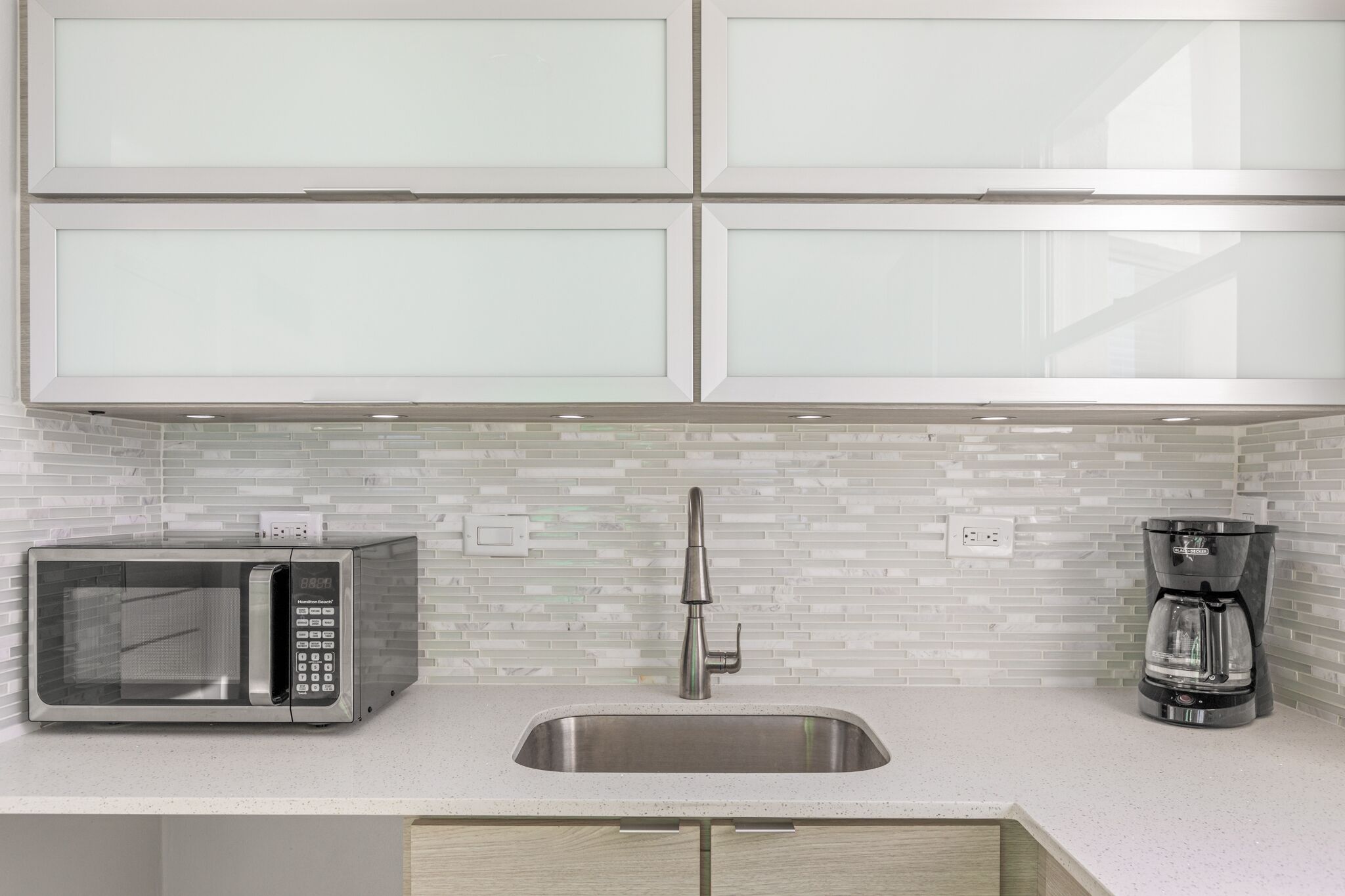 A kitchen with a stainless steel sink, a microwave, and a coffee maker.