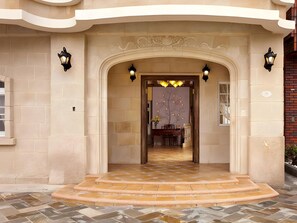 A building entrance with a stone facade, a tiled floor, and a decorative archway. - Brittany Hotel (Hengchun)