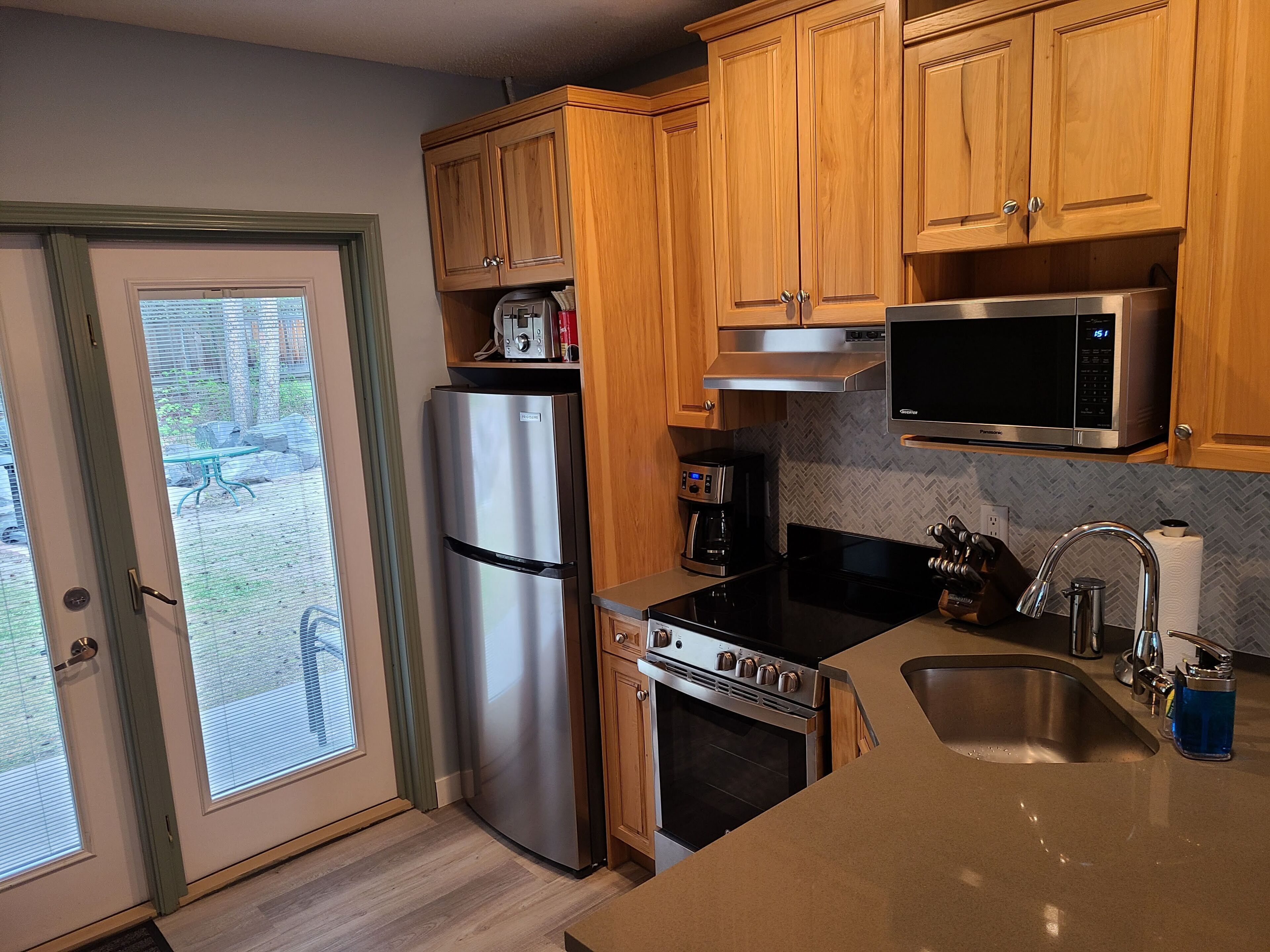 A kitchen with wooden cabinets, stainless steel appliances, a microwave, and a sink.