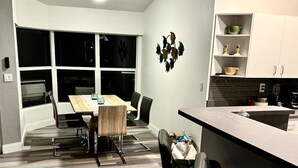 Eine moderne Küche mit Bar, einem Esstisch mit Stühlen und einem großen Fenster.