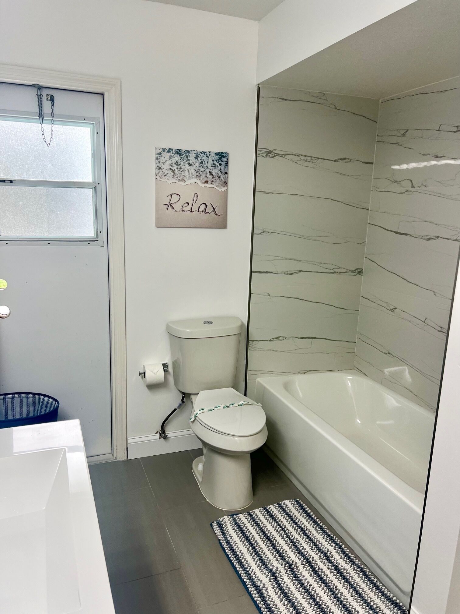 Ein Badezimmer mit Toilette, Badewanne und Dusche. Ein Handtuchhalter und ein Bild sind an der Wand zu sehen.