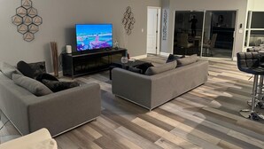 Ein modernes Wohnzimmer mit Flachbildfernseher, grauen Sofas und Holzboden.