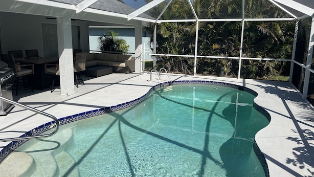 Ein überdachter Pool mit einer Terrassenanlage, einschließlich einer Sitzecke und einem Grill.