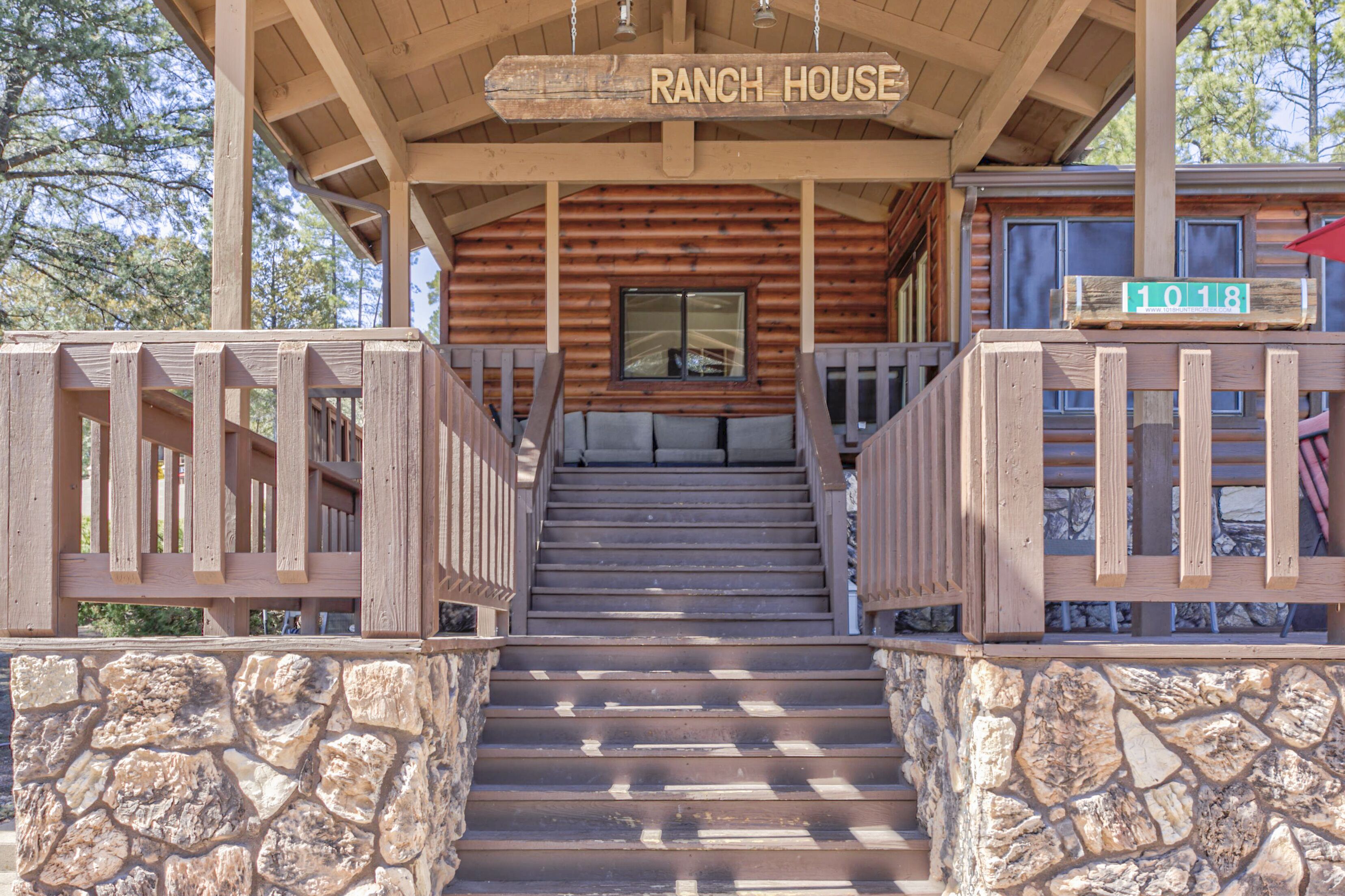 Una escalera de madera conduce a un porche cubierto con un letrero que dice 'RANCH HOUSE'.
