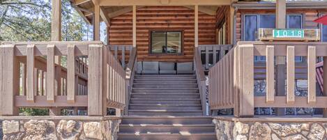 Una escalera de madera conduce a un porche cubierto con un letrero que dice 'RANCH HOUSE'.