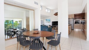 Ein moderner, offener Wohnbereich mit Essbereich, Küche und einem Balkon mit Blick auf Grünflächen.