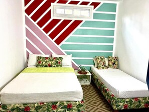 Ein Schlafzimmer mit zwei Betten, einer Wand mit Muster und einem kleinen Nachttisch mit Pflanze.
