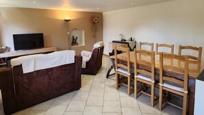 A living room with a sofa, TV, dining table, and chairs. - Chez la Lise - TANCON (TANCON)