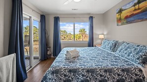 Un dormitorio con una cama grande, un ventilador de techo y vistas al exterior a través de una puerta corredera.