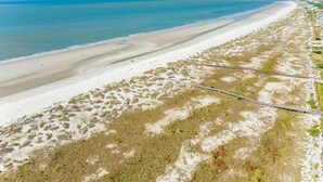 Una playa costera con orilla arenosa, un camino estrecho y vegetación escasa.