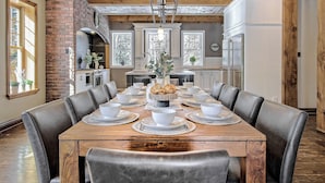 A dining room with a wooden table set for a meal, surrounded by leather chairs.