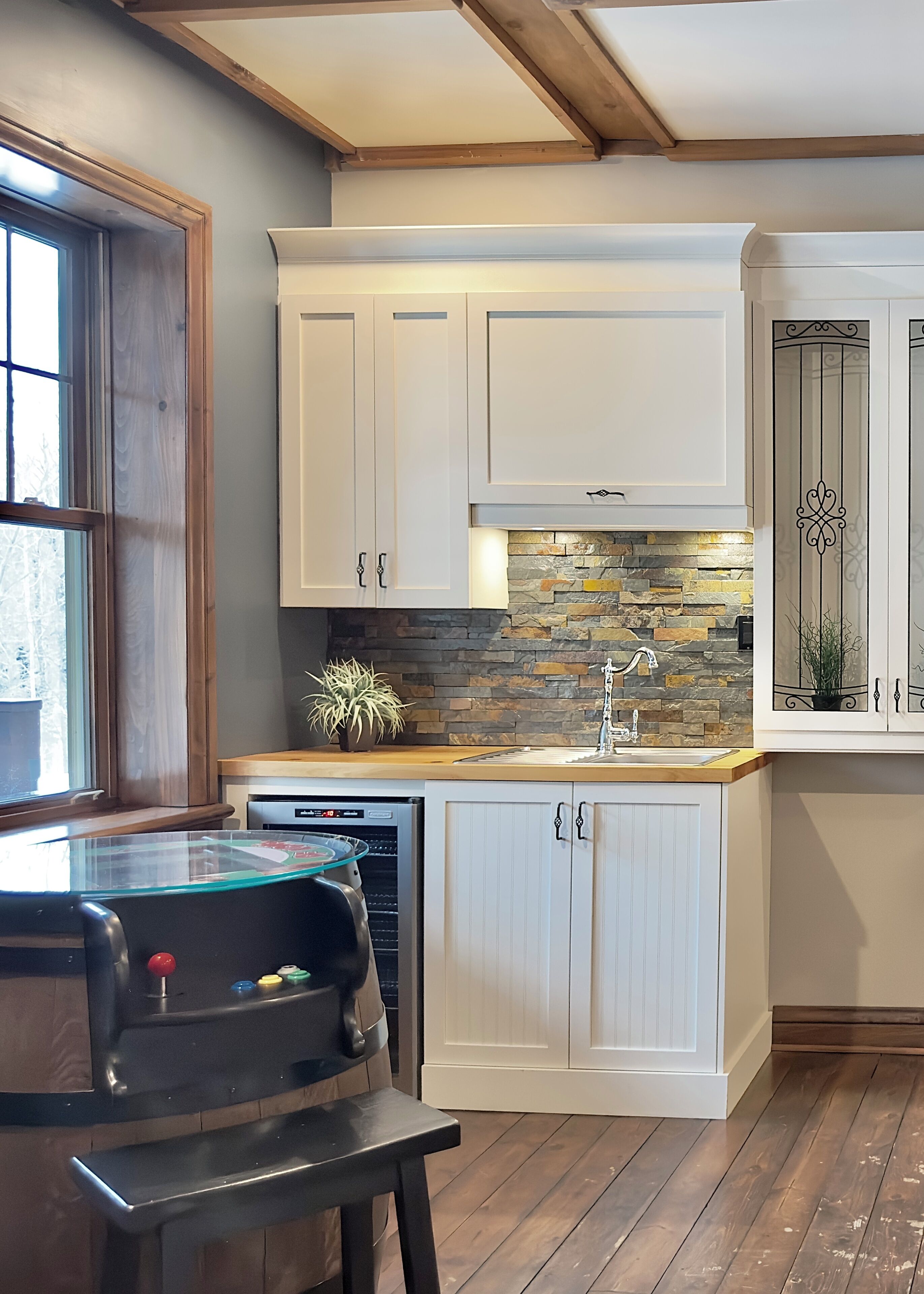 A kitchen with white cabinets, a stone backsplash, and a built-in dishwasher.