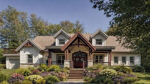A two-story house with a front porch, a stone foundation, and a well-maintained garden.