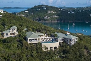 A coastal property with multiple buildings, a swimming pool, and a view of the sea with boats.