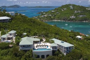 A resort with multiple buildings, a swimming pool, and a view of the ocean.
