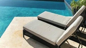 Un área de descanso junto a la piscina con vista al océano y una isla distante.