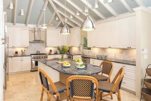A kitchen with white cabinets, a central island with seating, and pendant lighting. - Maria Bluff Estate | 7-Bedroom Villa | Generator (Cruz Bay)