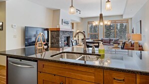 A modern kitchen with a large island, stainless steel appliances, and pendant lighting. - Picturesque Views | Creekside Walking Paths to Town (Canmore)