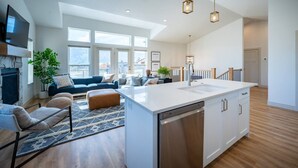A modern kitchen with a large island, a dining area with a sofa, and a living room with a fireplace. - Private Powder Mtn B2 | Desk| Hot Tub| Ski Retreat (Eden)