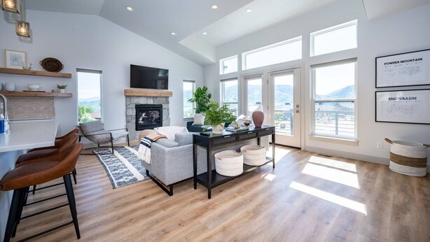 A spacious living room with a fireplace, a dining area with bar stools, and large windows offering a view of the mountains. - Private Powder Mtn B2 | Desk| Hot Tub| Ski Retreat (Eden)