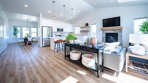 A spacious living area with a fireplace, a dining table with chairs, and a kitchen with modern appliances. - Private Powder Mtn B2 | Desk| Hot Tub| Ski Retreat (Eden)