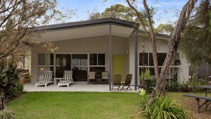 Una casa moderna con un portico coperto, area salotto esterna e un giardino curato.