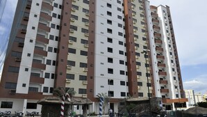 A multi-story residential building with balconies, a central entrance, and a small outdoor seating area with tables and chairs. - Golden Dolphin Supreme - Achei Férias (Caldas Novas)