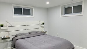 Een moderne slaapkamer met een bed, nachtkastjes en een hoofdbord met ingebouwde planken.
