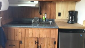 A kitchen with wooden cabinets, a dishwasher, a coffee maker, and a sink. - Cozy Condo close to Sesuit (Dennis)