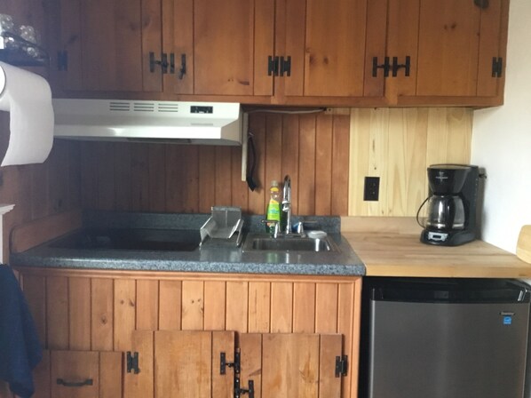 Una cucina con mobili in legno, lavastoviglie, macchina da caffè e lavello.