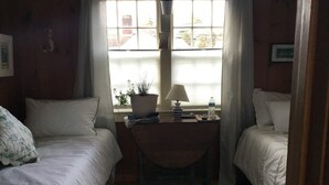 A room with two beds, a small table with a lamp, a potted plant, and a view through a window. - Cozy Condo close to Sesuit (Dennis)