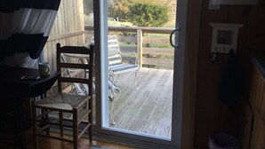 A room with a wooden deck, a chair, and a table with a mug. - Cozy Condo close to Sesuit (Dennis)