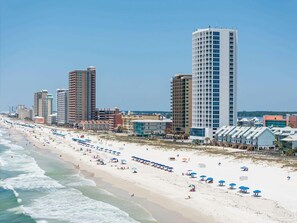 A beach with rows of umbrellas and a row of high-rise buildings in the background. - ISLAND TOWER 502 BEACH FRONT 3 BEDROOMS 3 BATHS (Gulf Shores)