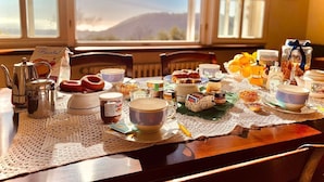 Ein Frühstückstisch reichhaltig gedeckt mit Speisen und Blick auf eine Berglandschaft durch ein Fenster.