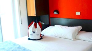 Ein Hotelzimmer mit einem Bett, einem Koffer auf dem Bett, einem Bild an der Wand und einem Fenster mit Blick.