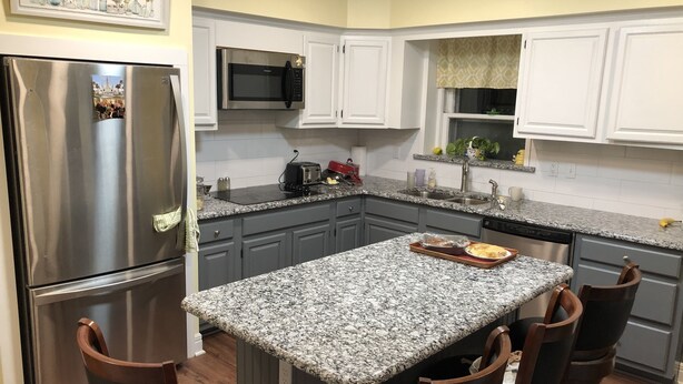 A kitchen with granite countertops, stainless steel appliances, and wooden chairs. - The Estate Room at Shoal Creek B&B (Hamilton)