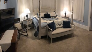 A four-poster bed with a canopy, two bedside tables with lamps, a rocking chair, and a bench with pillows. - The Estate Room at Shoal Creek B&B (Hamilton)