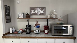 A kitchen counter with a coffee maker, a red coffee pot, a microwave, and a shelf with mugs and a 'grateful' sign. - Private Country Farmhouse (Winnsboro)