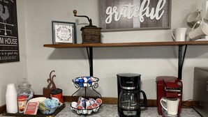 A kitchen counter with a coffee maker, a red coffee machine, a milk frother, a tray of coffee pods, and a jar of coffee creamer. - Private Country Farmhouse (Winnsboro)