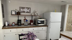 A kitchen with a microwave, coffee maker, and a refrigerator. There is a shelf with decorative items and a sign that says "grateful". - Private Country Farmhouse (Winnsboro)