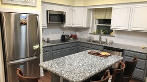 A kitchen with granite countertops, stainless steel appliances, and wooden chairs. - The Cottage Room at Shoal Creek B&B (Hamilton)