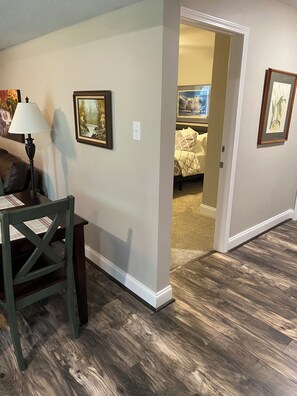 A hallway with a dining table, chairs, and framed artwork on the walls.