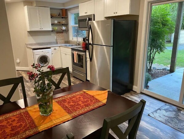 A modern kitchen with white cabinets, stainless steel appliances, and a dining area with a table set for two.