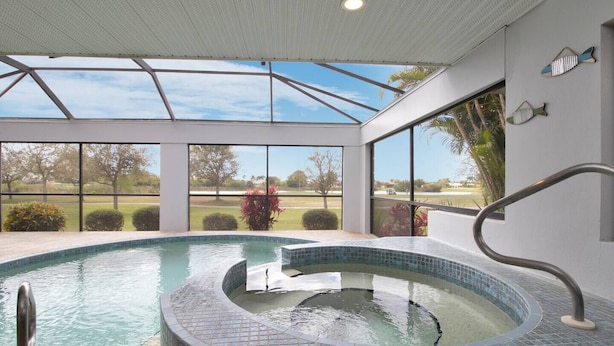 A swimming pool with a hot tub, large windows, and a view of the outdoors. - Feels Like Home - w/ Heated Pool Book Now! (Punta Gorda)