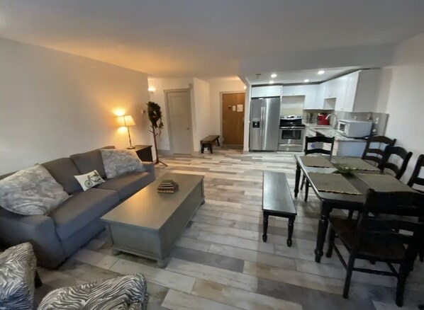 A modern living room with a sofa, coffee table, and dining area with chairs and a table.