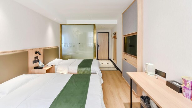 A hotel room with two beds, a desk, a TV, and a bathroom visible through a glass door. - Greentree Inn Hefei Fanhua Avenue Juece Building B (Hefei)