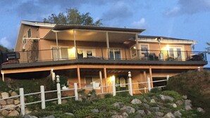 Una casa de dos pisos con un balcón, un porche cubierto y una cerca blanca al frente.