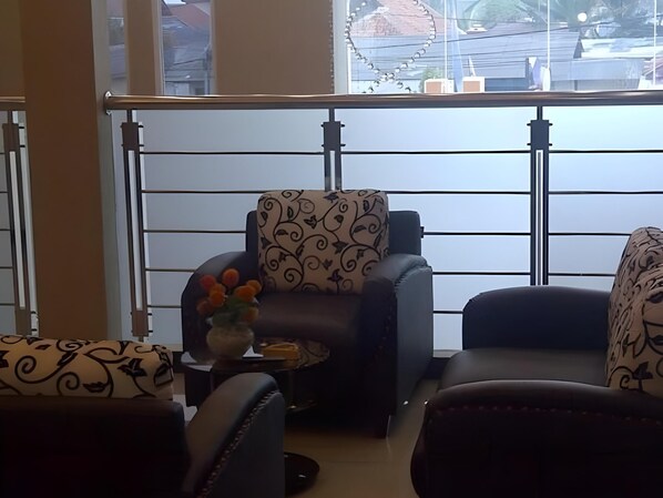 A balcony with a view of a bridge and buildings, furnished with two armchairs and a small table with a vase of flowers.