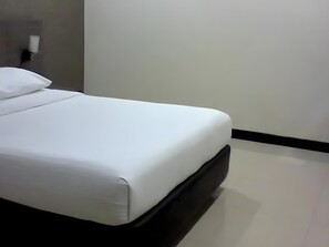 A bed with white bedding in a room with a black headboard and a white wall.